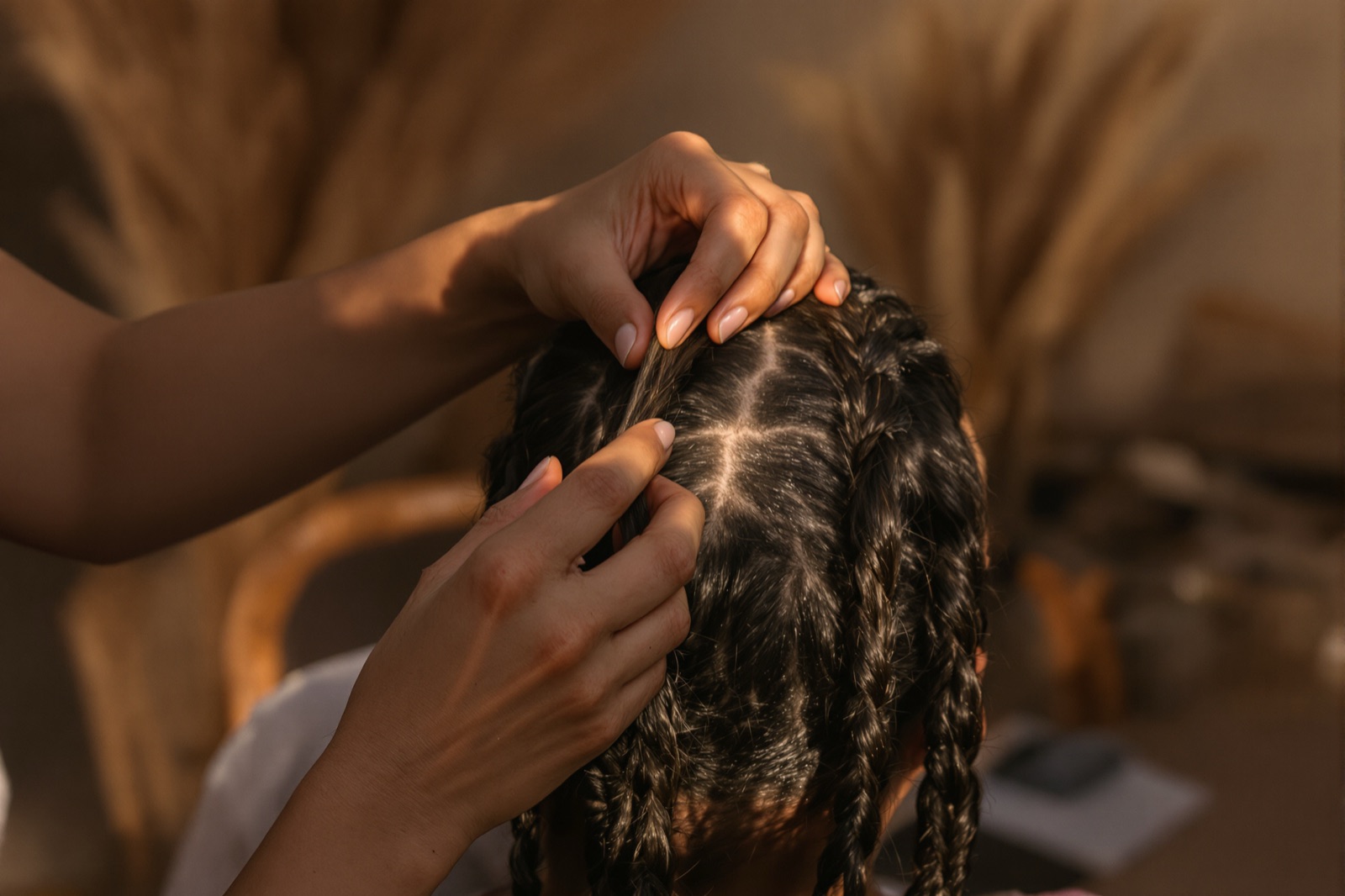 Hands braiding hair into neat sections